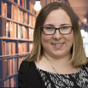 a smiling white woman with glasses and shoulder length light brown hair in front of long bookshelves 